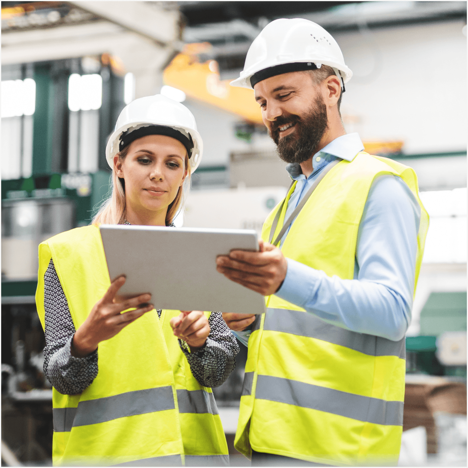 Two people looking at an ipad on a construction site