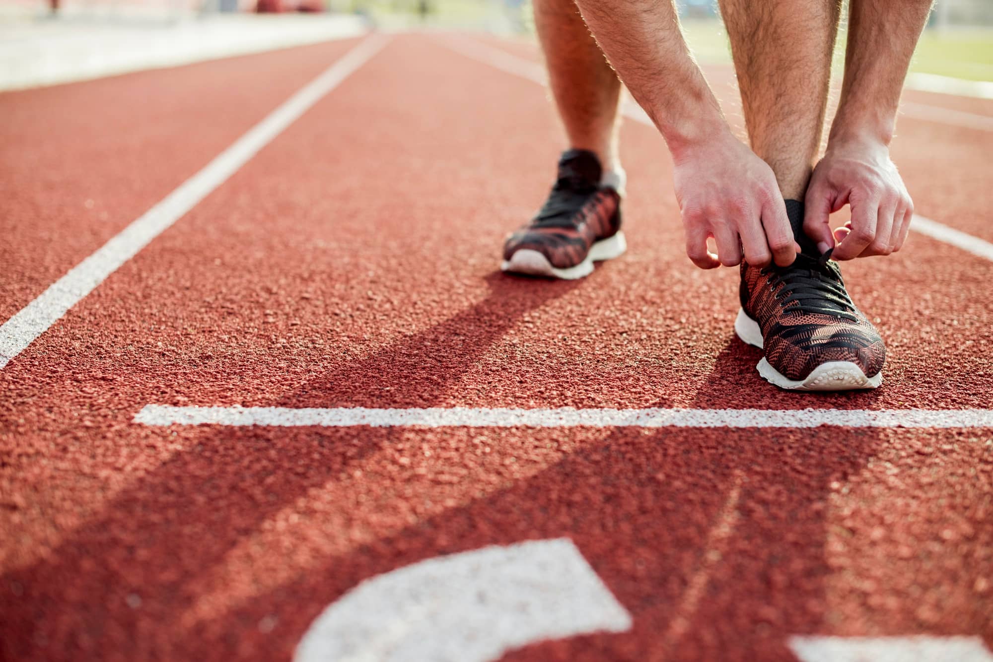 A man adjusting his shoe on a running track
