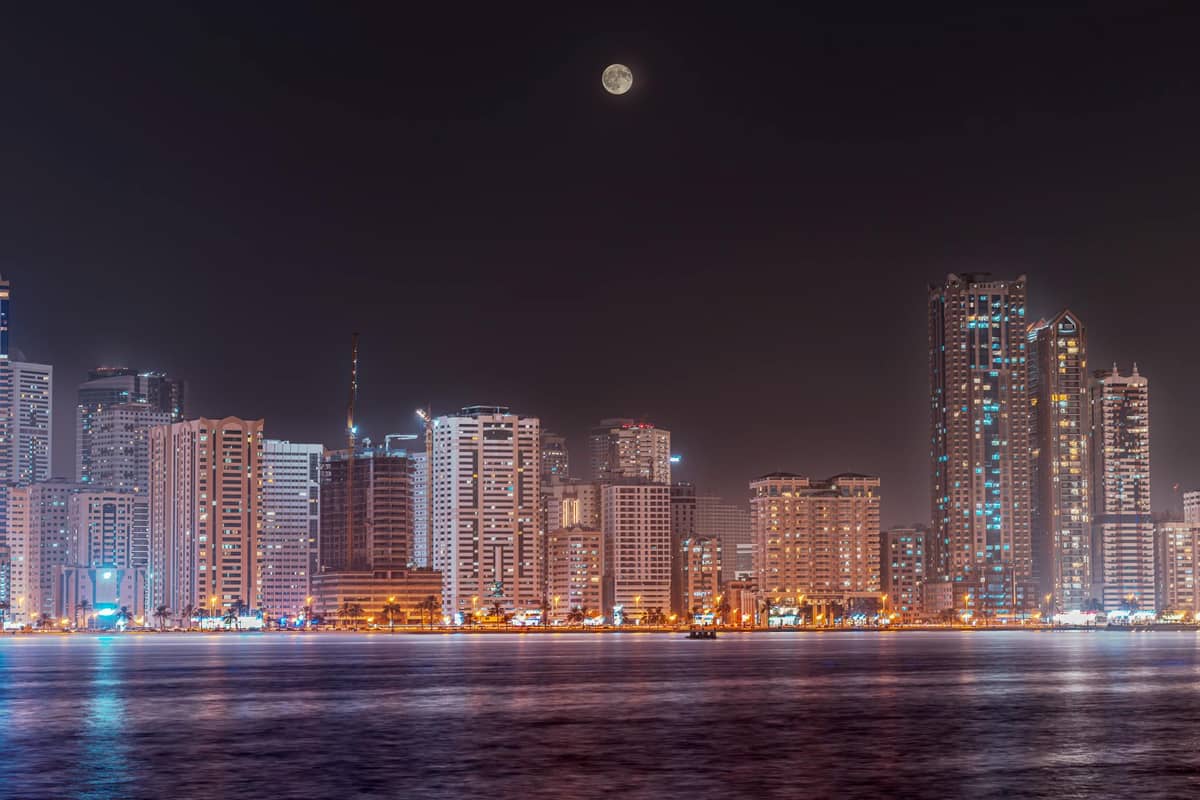 Sharjah's skyline at night on a full moon; Arch is advertising the accessible web development Sharjah might be seeking. 