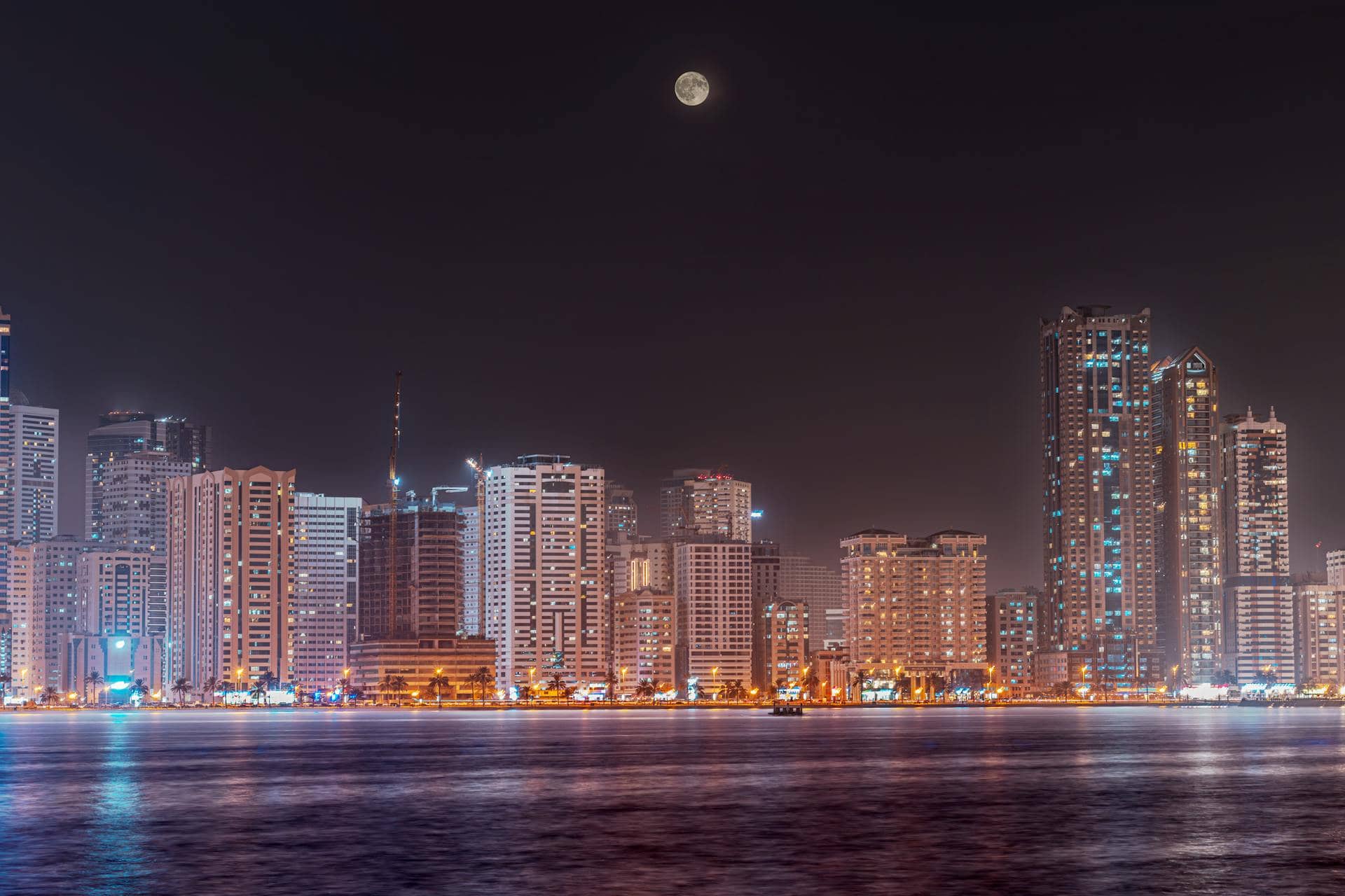 Sharjah's skyline at night on a full moon; Arch is advertising the accessible web development Sharjah might be seeking. 