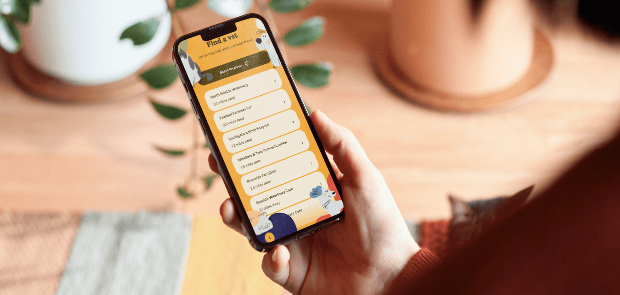 Paws and protect mobile app on phone in persons hand with cat